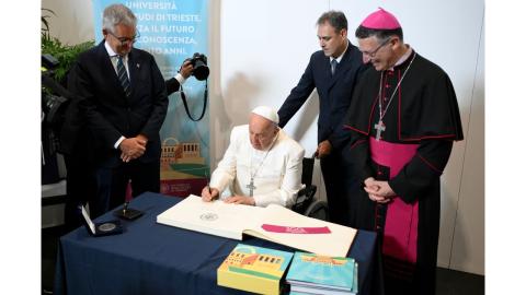 Papa Bergoglio frima il libro d'onore di UniTS davanti al rettore Di Lenarda e al vescovo Trevisi