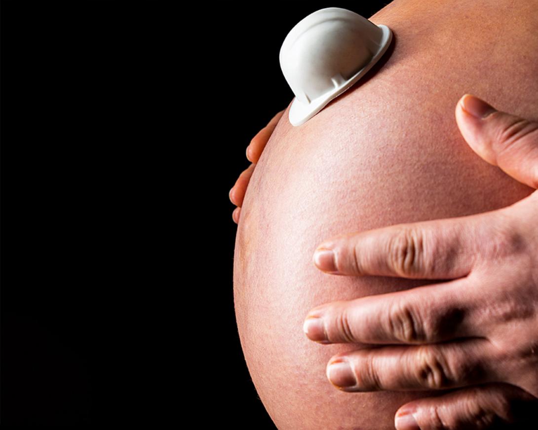 pancia di donna incinta con casco da cantiere