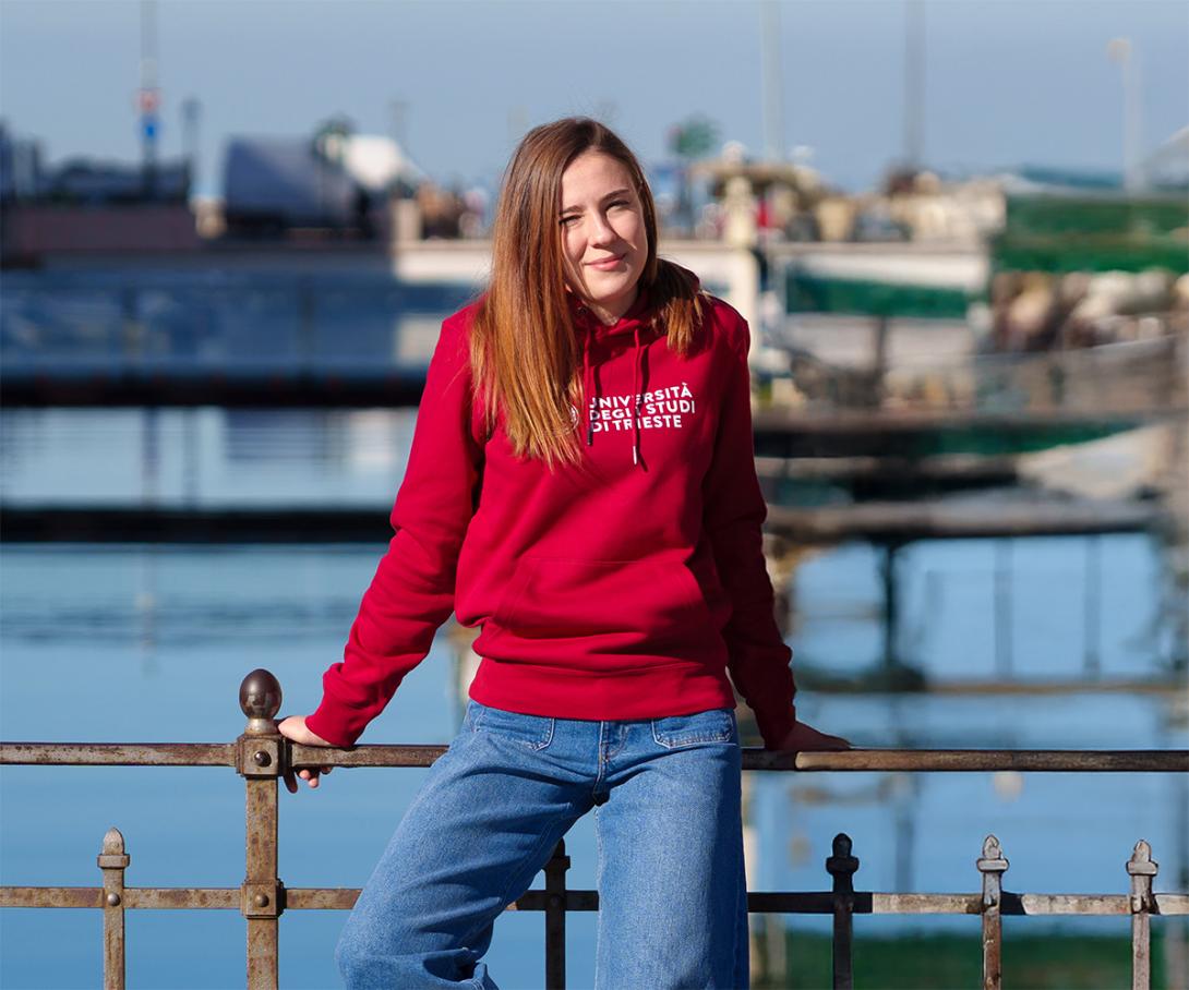 studentessa con felpa con cappuccio rossa. sullo sfondo il canale di Ponterosso